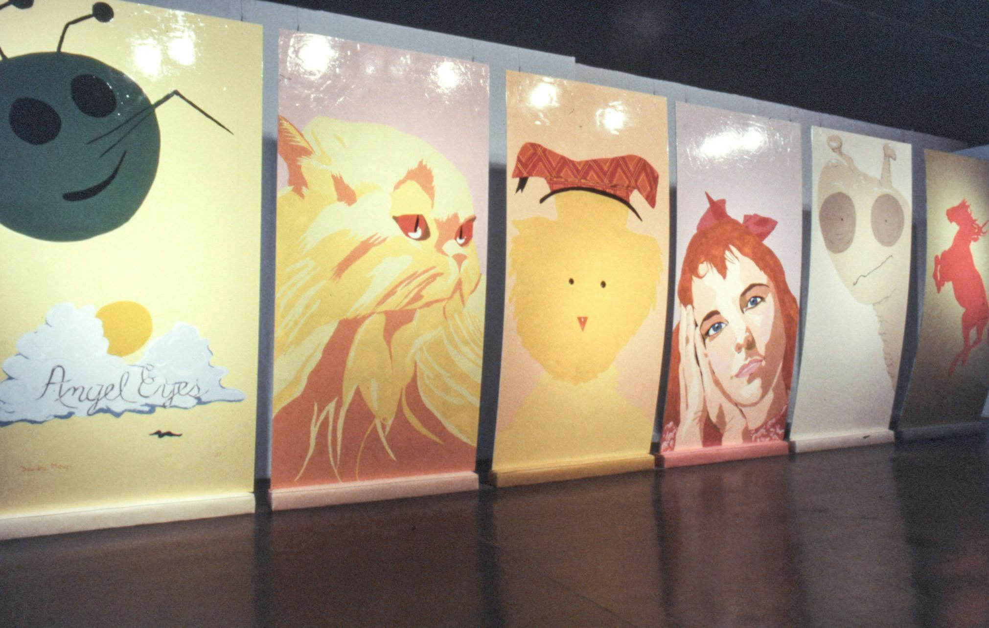 A closeup of large glossy paintings suspended in front of a wall. The paintings are narrow and very tall They show different images of a mosquito, a cat, a chick, a human, a snail, and a horse.