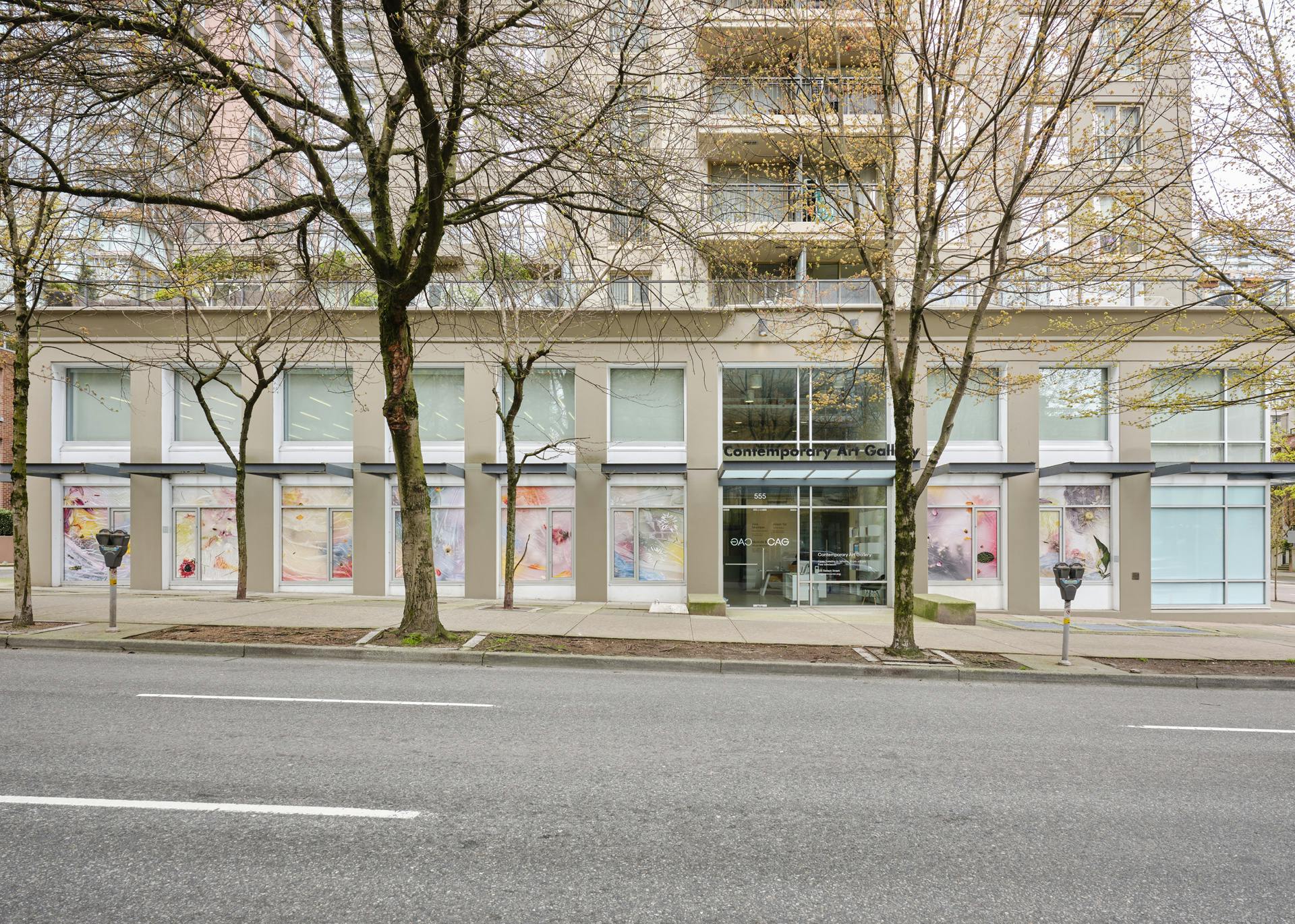 A view of the Contemporary Art Gallery building from across the street. The windows are  covered with vinyl photographs depicting diffuse colour,  indecipherable plant matter and wrinkled plastics. 
