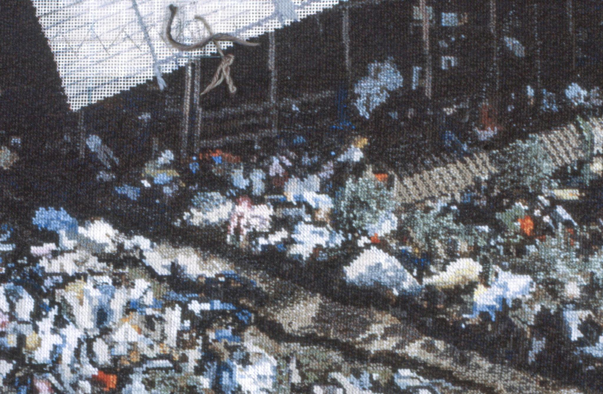 A closeup of an embroidered carpet, showing the Jonestown massacre. The detail shown includes bodies on the grass and under the shade of the large building shown. 