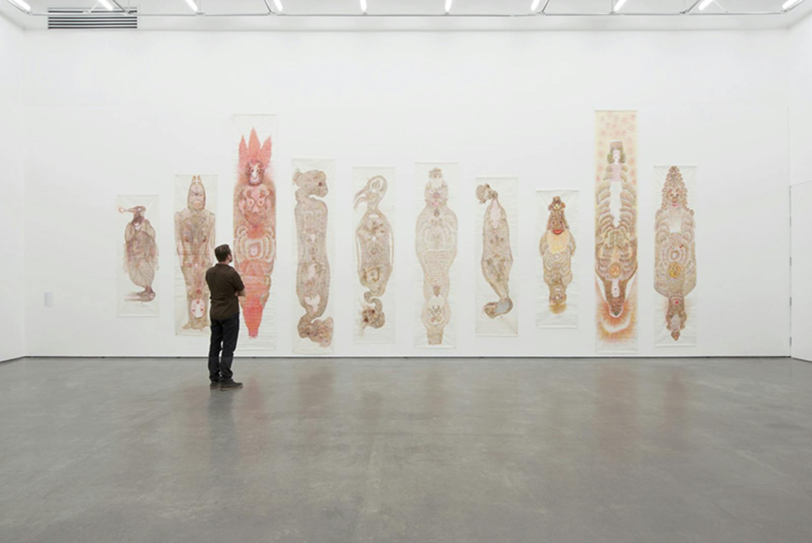 Ten drawings by Guo Fengyi on long, narrow sheets of paper larger than human scale installed in a gallery. The images resemble imaginary human, animal or mythical figures.