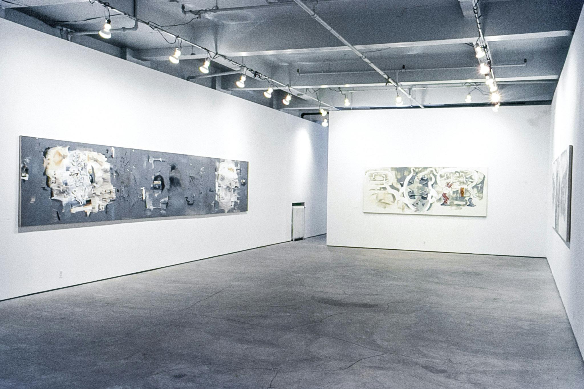 A gallery space with several large paintings mounted on the walls. The paintings are abstract and highly detailed, incorporating different shades of grey, red, yellow, and black and white. 