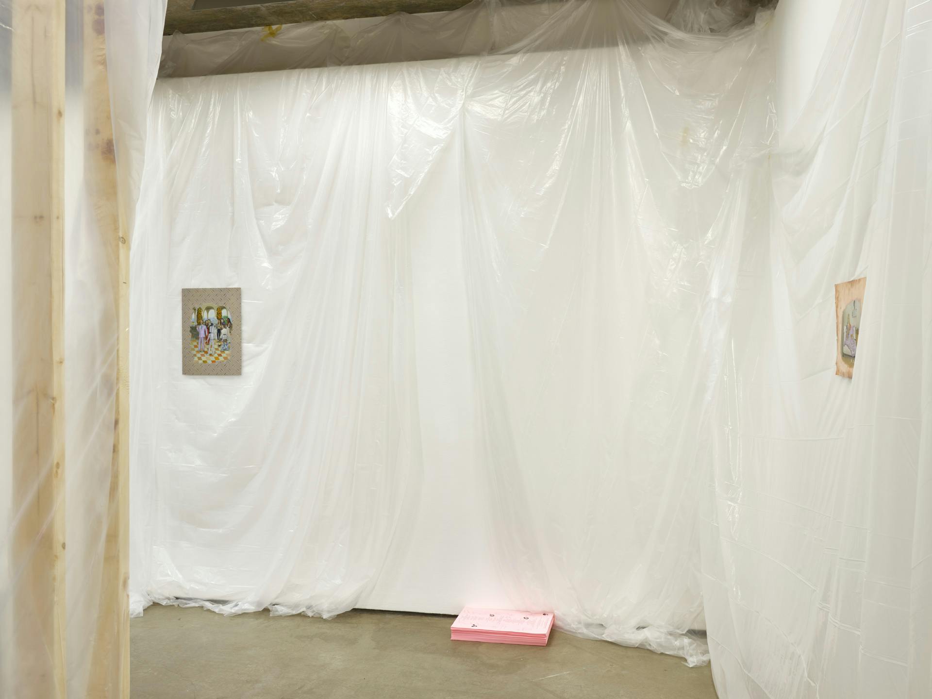 A corner view of two small paintings on metal sheets hanging on gallery walls draped in translucent plastic. A stack of bright pink papers sits on the floor at the base of the wall. 