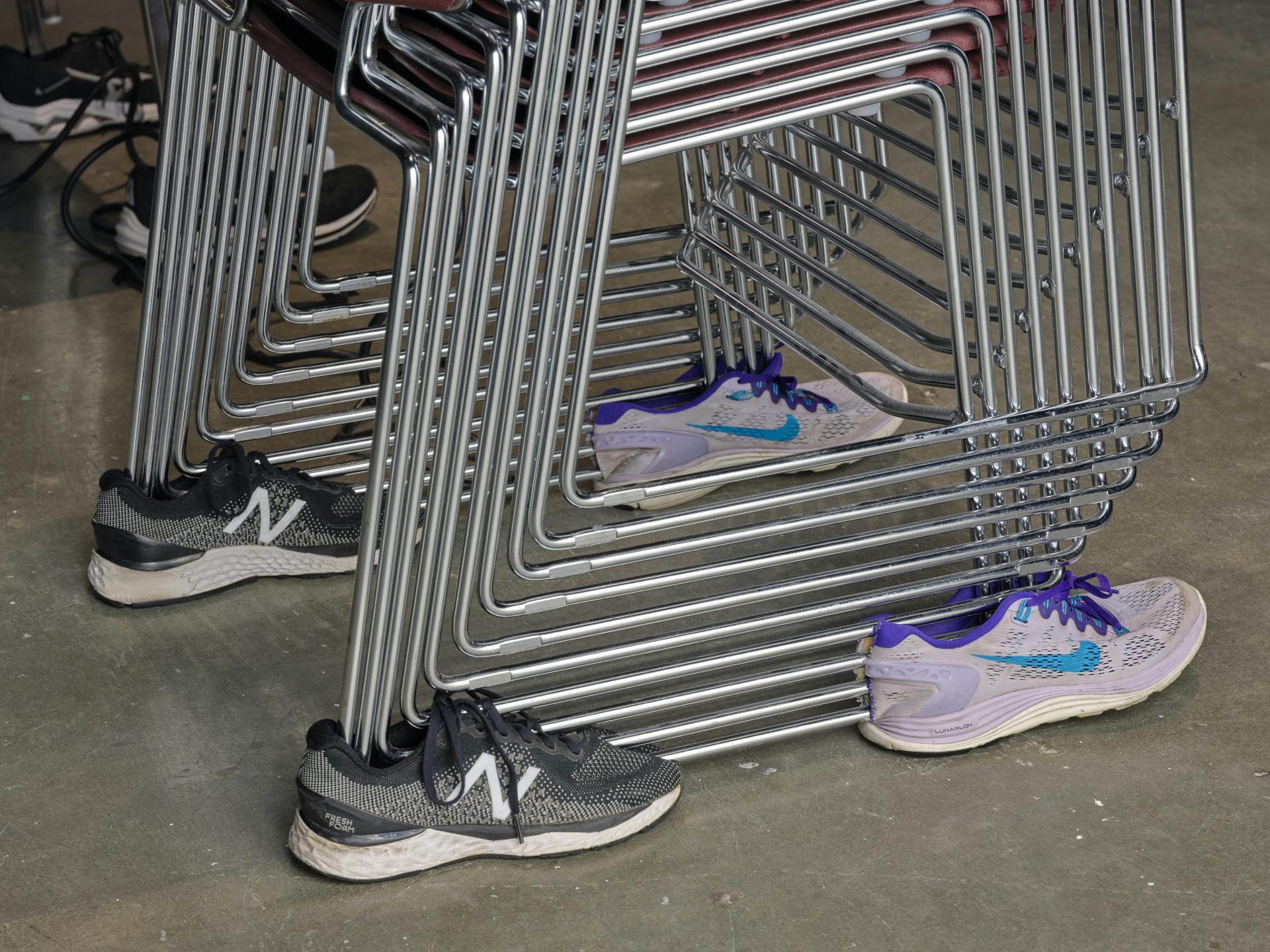 Four running shoes supporting at its corners a stack of chairs.