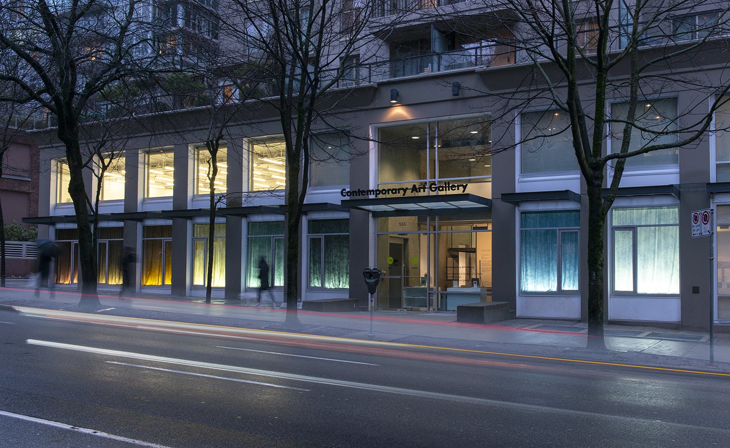 Exterior image of the Contemporary Art Gallery displaying the work of Nicole Kelly Westman in the windows. The eight windows on the first floor are lit, highlighting various coloured backdrops.