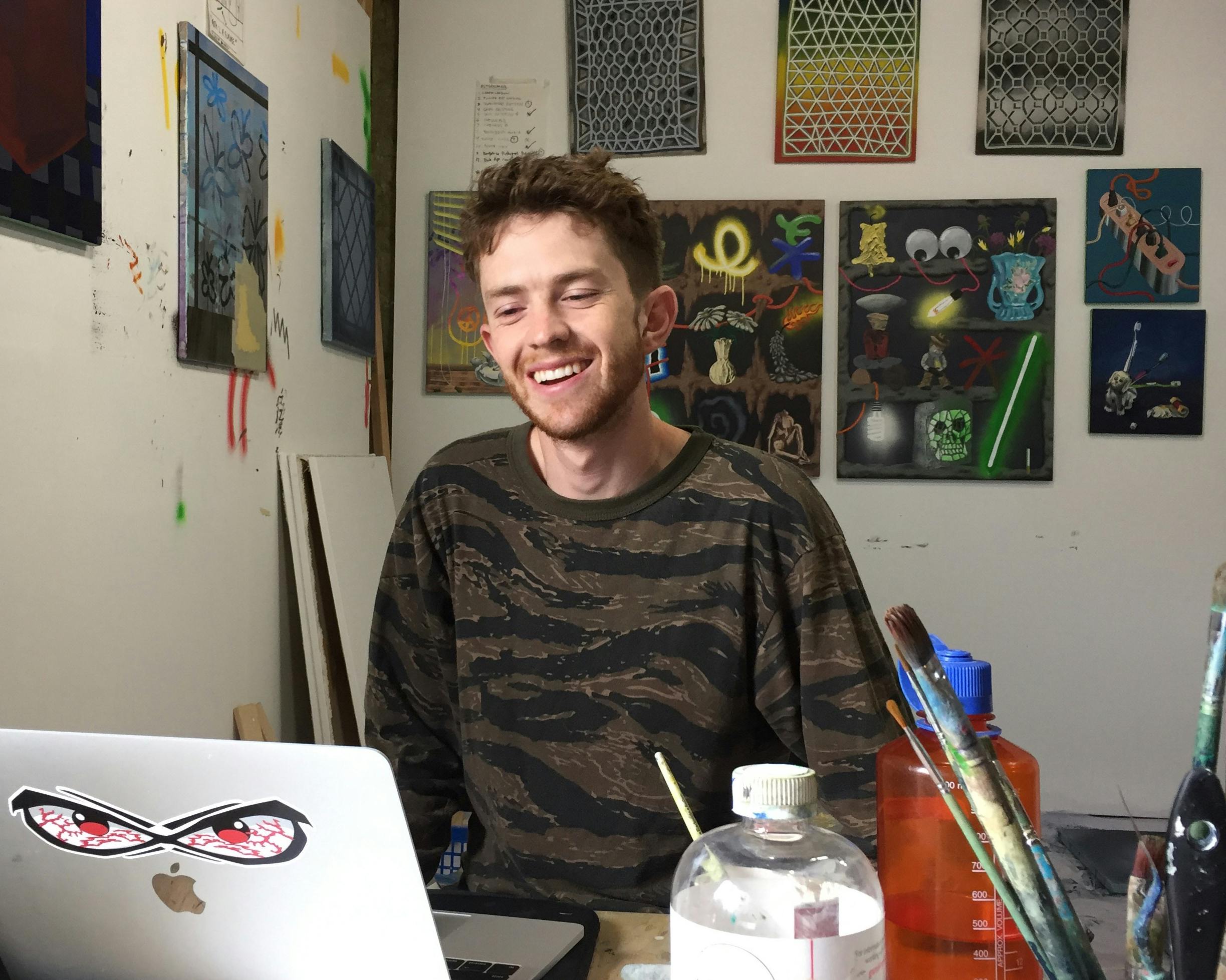 A photo of Jack Kenna sitting in his studio and speaking to his laptop. 