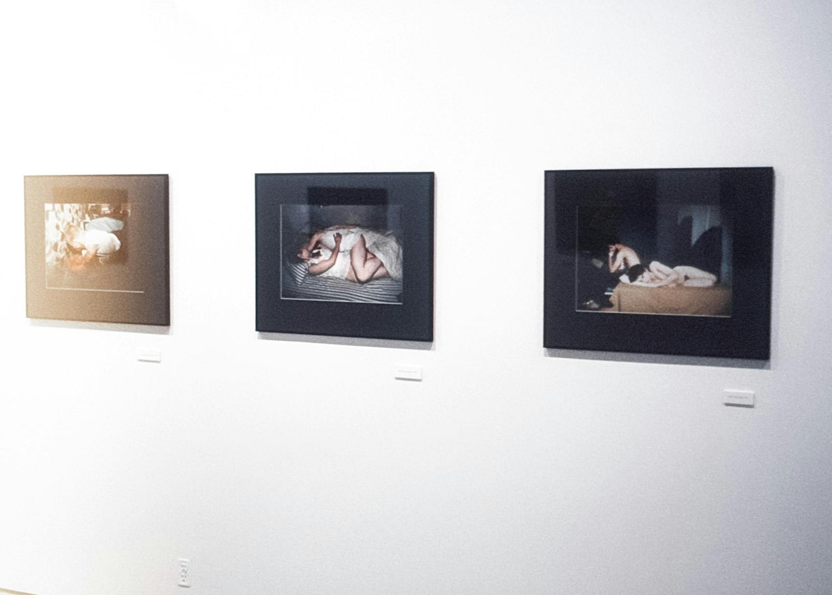 Three framed photo works on a white wall. All photos are of different couples. From left to right, the couples go from dressed to nude they appear to be dancing, having sex, and resting together.