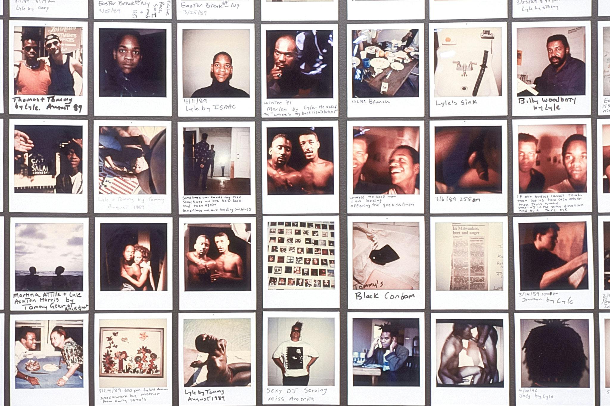 A closeup of several Polaroid photos on a black wall. Some photos are captioned and some are not. All depicts snippets of Black Queer life, including plates of food, smiles, kisses, genitals and hugs.