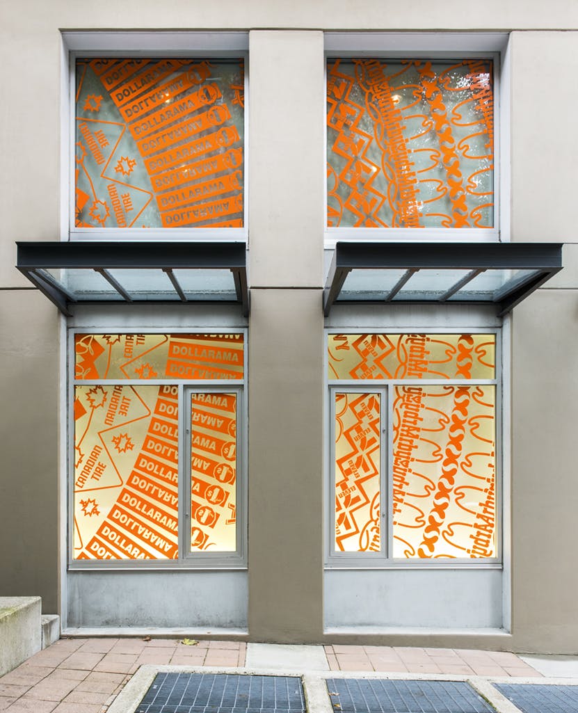 Detail image of four exterior windows at CAG installed with a pattern by Gunilla Klingberg in orange cut vinyl. Logos of companies such as DOLLARAMA and Canadian Tire are incorporated into the design.