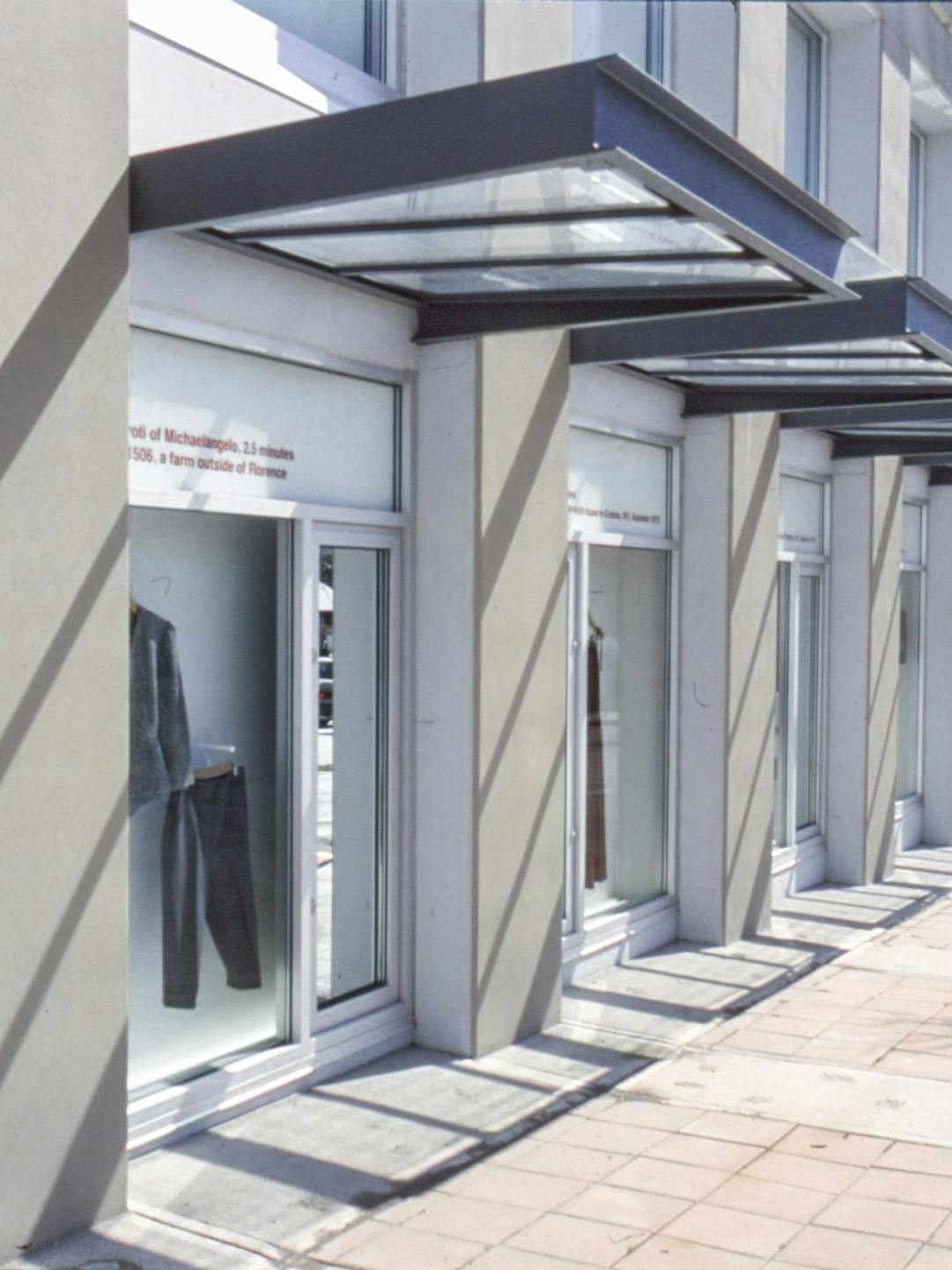Various outfits are displayed in CAG’s window spaces. The window which is closest to the camera displays a pair of grey sweatpants and a sweatshirt. 