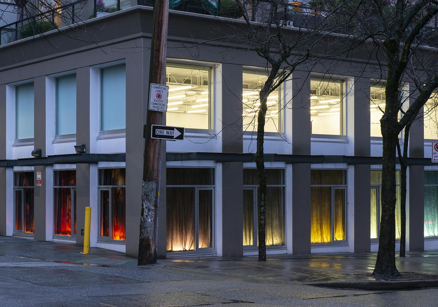 Exterior of the Contemporary Art Gallery displaying the work of Nicole Kelly Westman in the windows. The eight windows on the first floor are lit, highlighting various coloured backdrops.