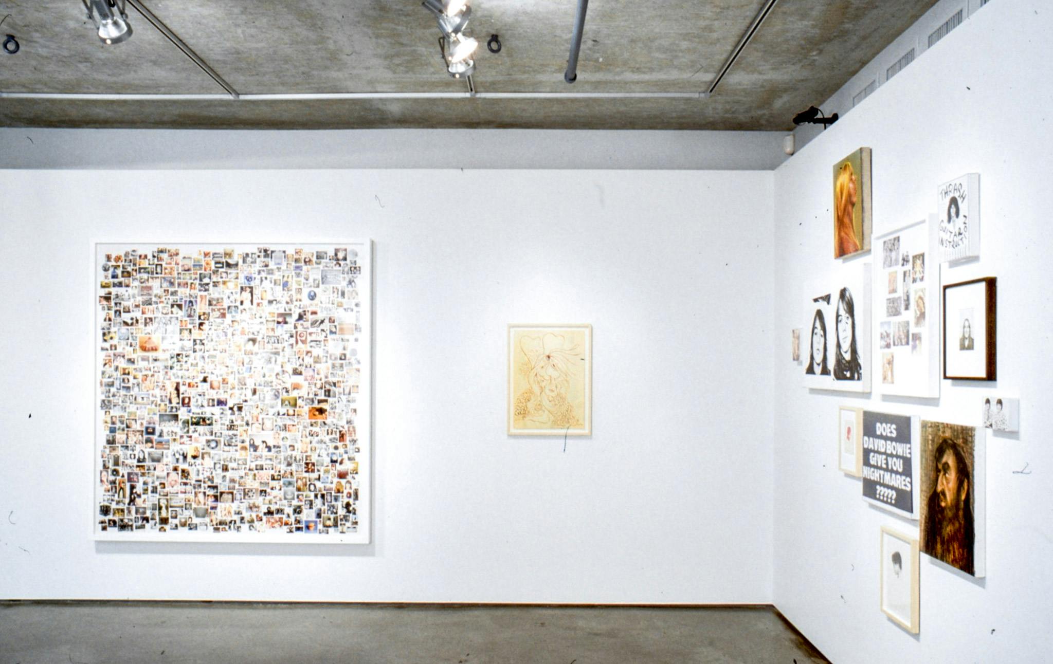 Installation image of works by Steven Shearer. Paintings, collage works, and photographs are mounted on the walls. On a far wall, a large photo collage work is installed.