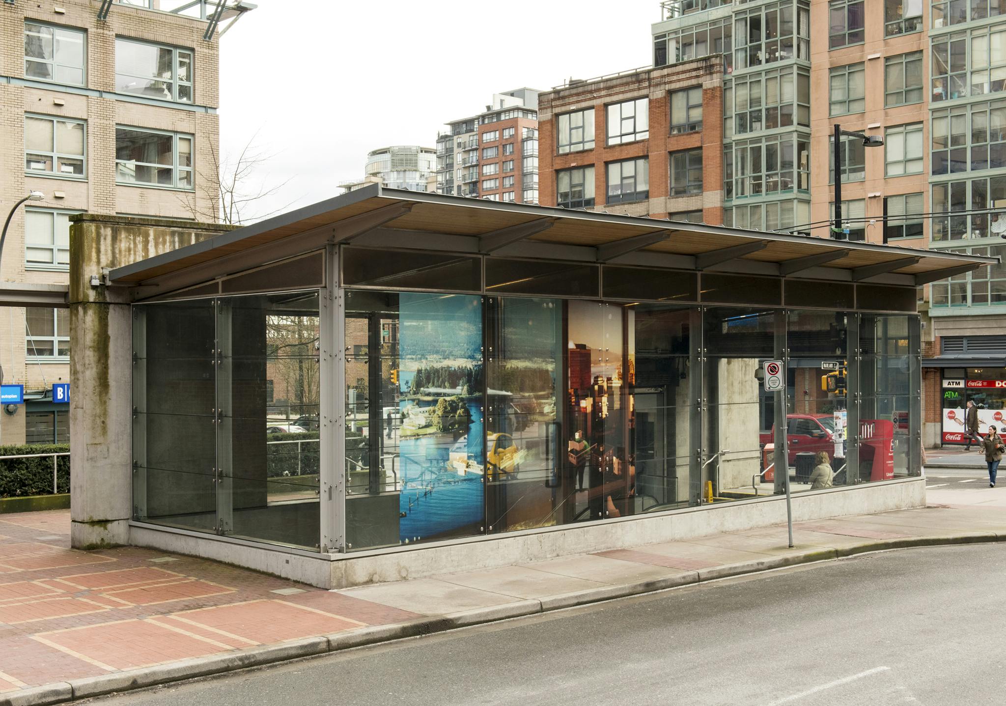 Installed on the glass facade at Yaletown Roundhouse Skytrain station are three, large-scale colour photographs in vinyl depicting aerial views of Vancouver at different times of the day. 