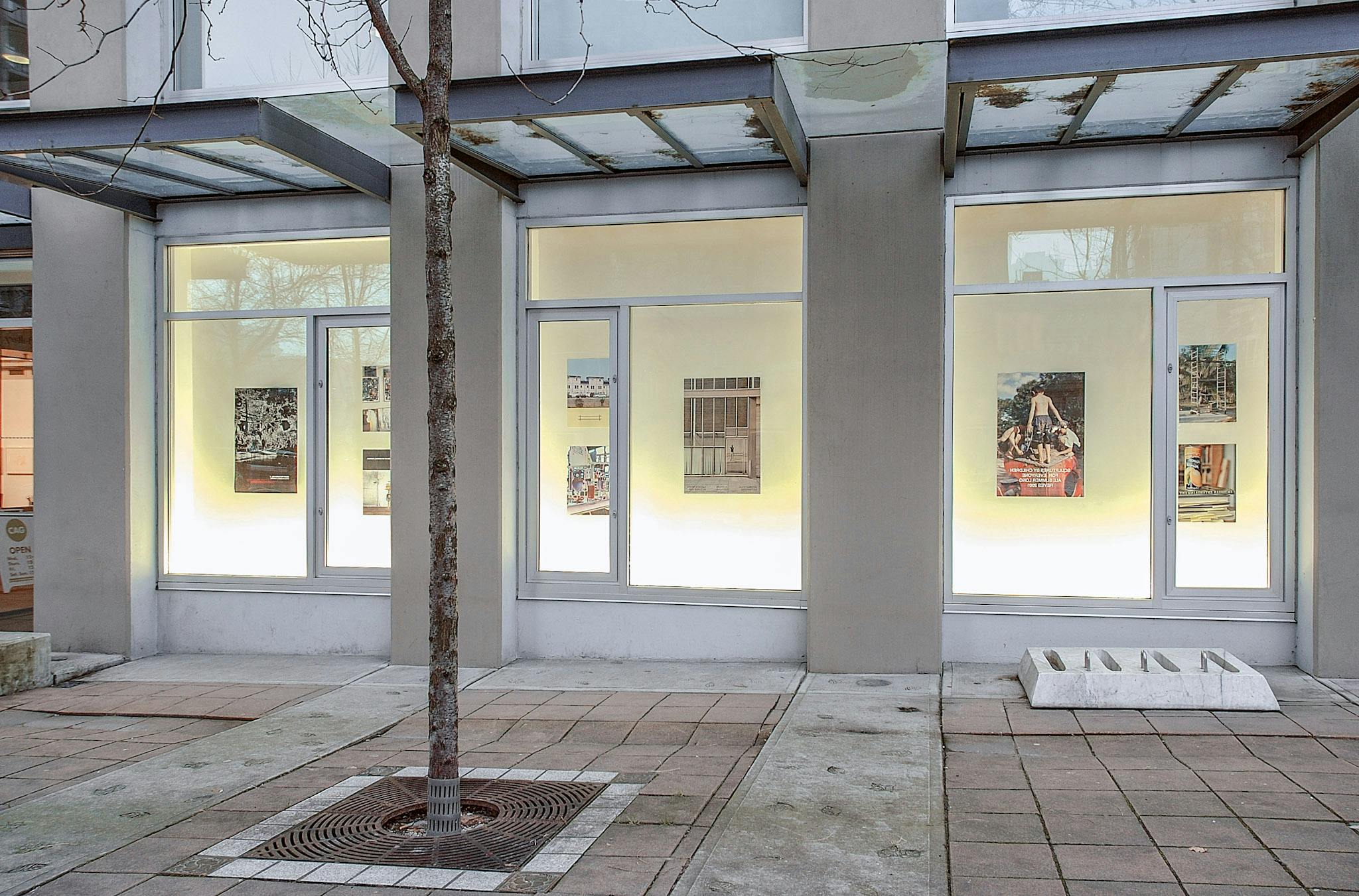 Each of the CAG exterior window spaces displays three various-sized posters made by Andrew Reyes. The images on those posters are the enlarged coloured photographs taken in outdoor settings.