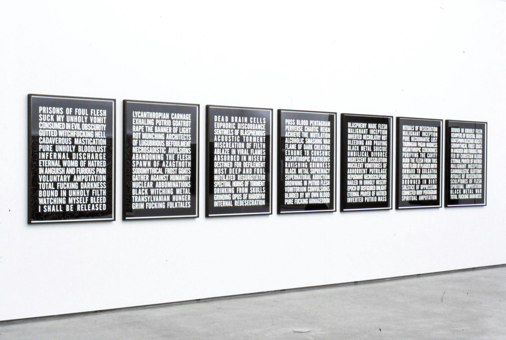 Installation image of works by Steven Shearer. Seven text-based works, on which English words appear in all capital letters in white on black background, are mounted on the wall.