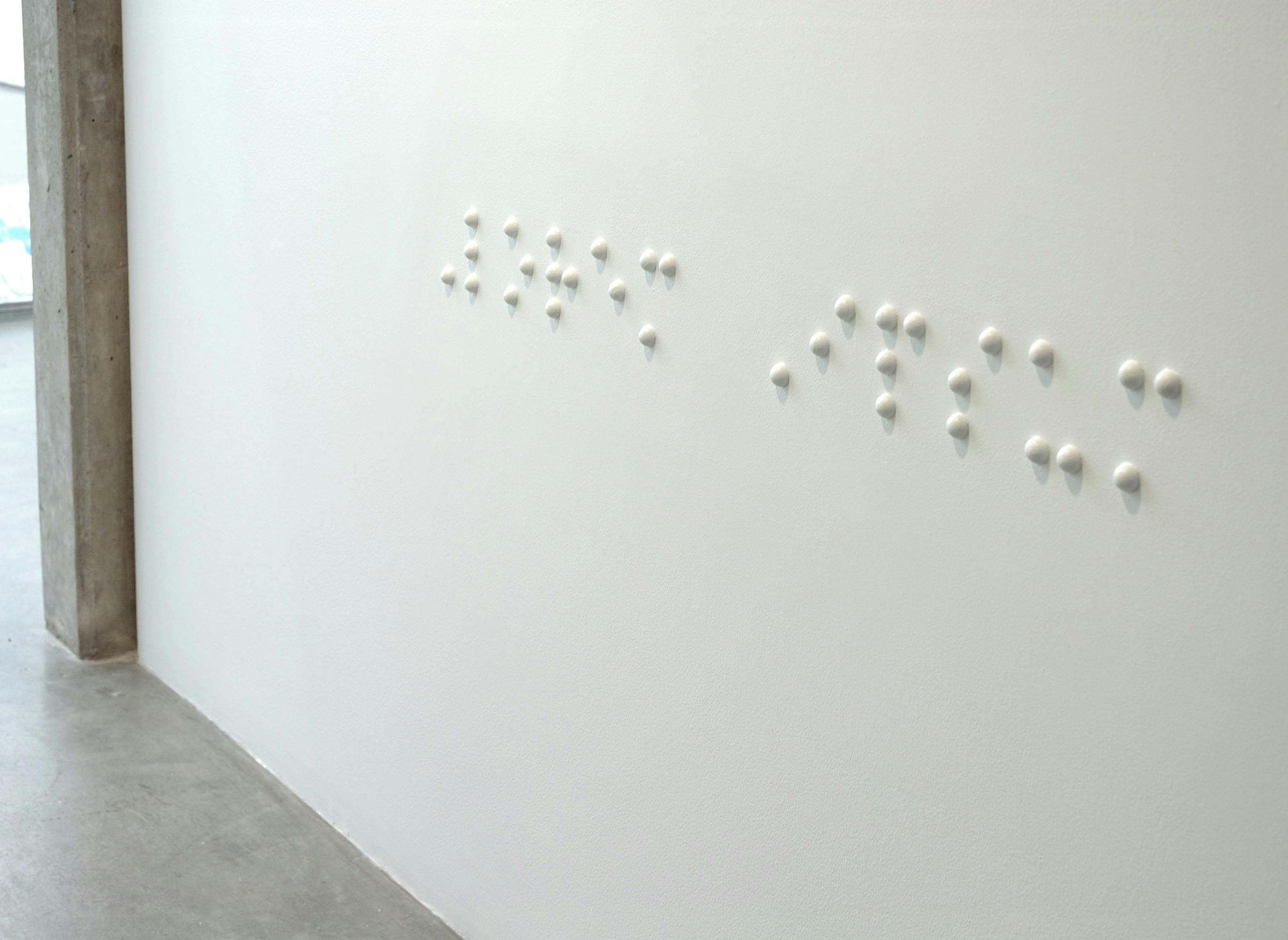Large-sized braille is installed on a white wall between CAG’s lobby to one of its gallery spaces. The braille is placed around the height where adults’ hands will be when they stand.
