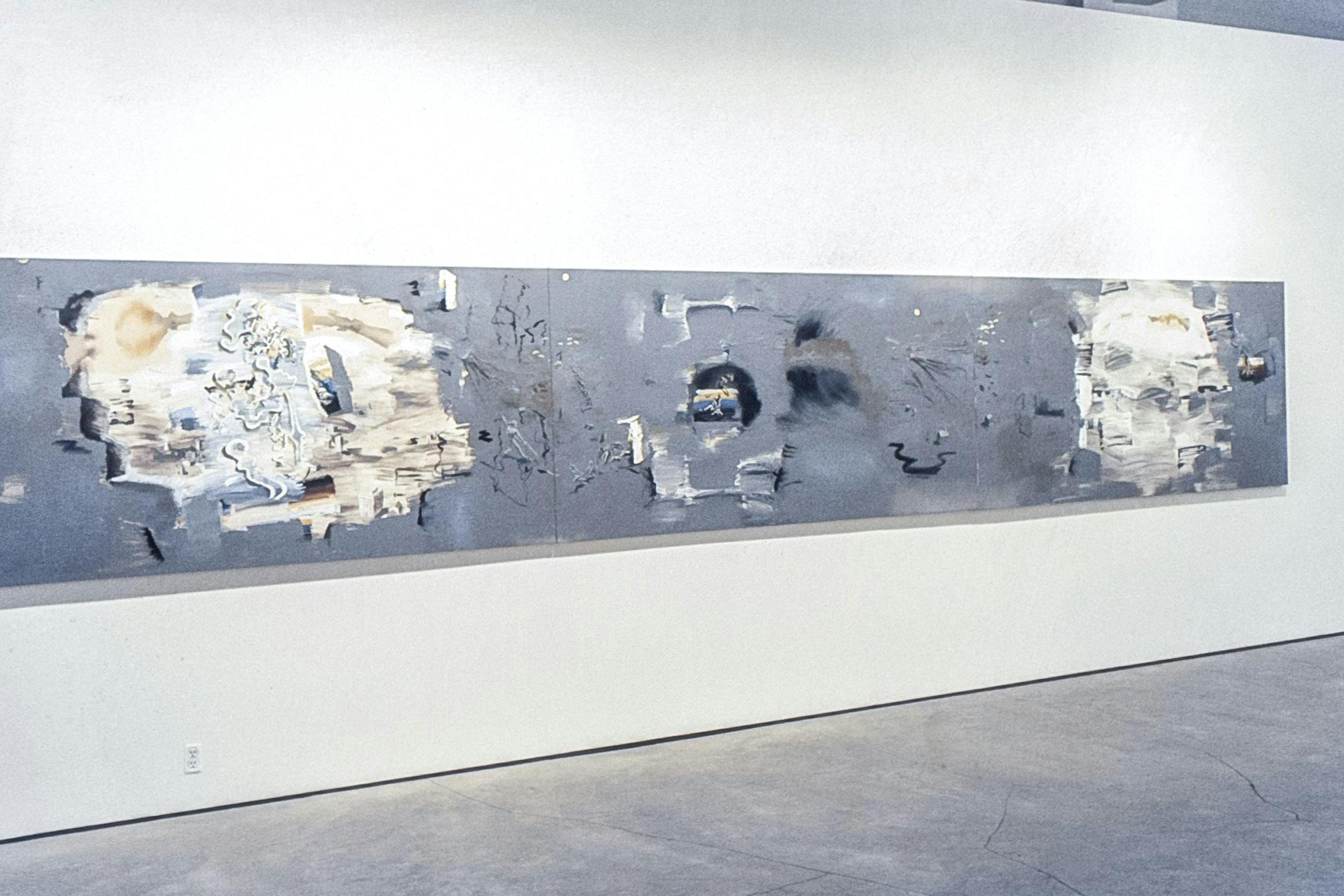 A large painting mounted on a white wall. The work is long, composed of three joint horizontal canvases. The background of the painting is grey with white, black, yellow, blue, and brown details.