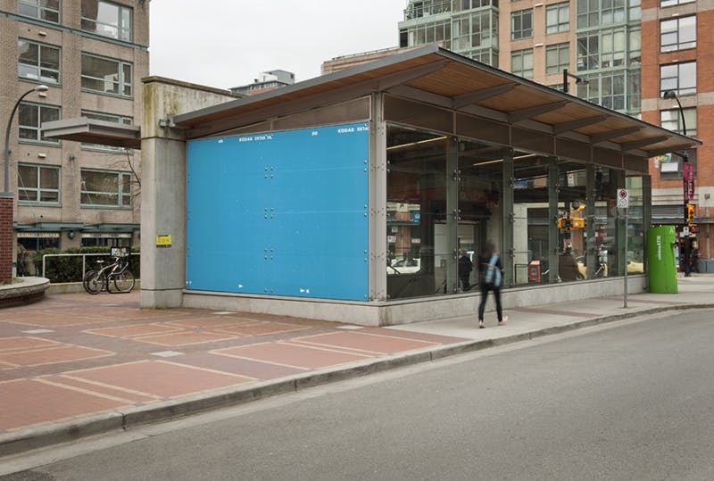 Scott Massey’s two-dimensional work installed on the window of the shorter side of Yaletown-Roundhouse Station. The image shows white stars in a blue background with KODAK EKTAR written at the top.