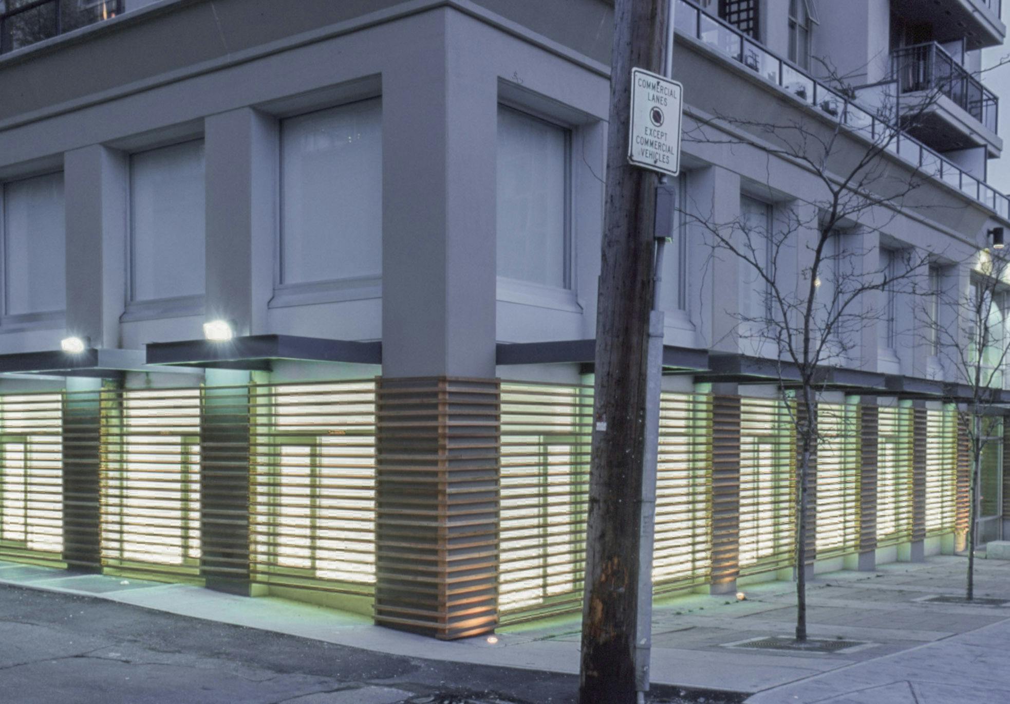 A set of sculptures that look like wooden fences covers the entire windows on CAG’s first floor. A number of horizontally arranged wooden bars cover the illuminated window spaces. 
