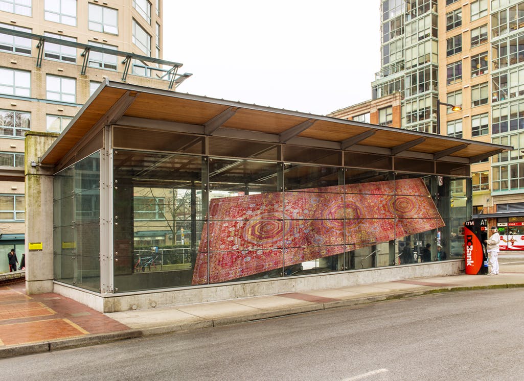 Installed on the facade of Yaletown-Roundhouse Station is a photograph in vinyl of a large rectangular carpet. The image is reproduced at a slanted angle, making the carpet look like it is flying.
